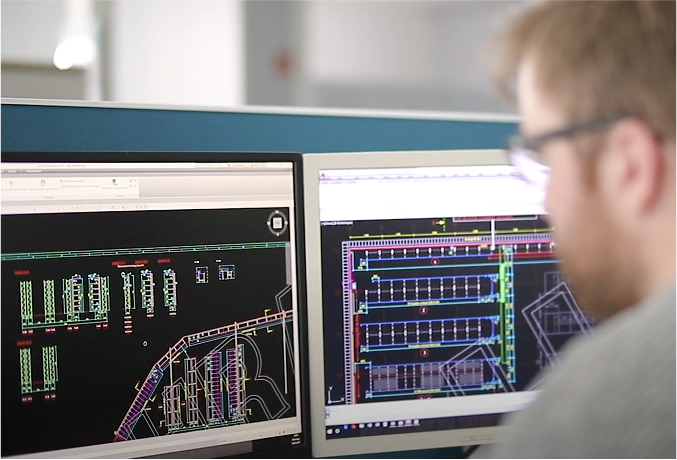 Mann betrachtet technische Details auf 2 Monitoren